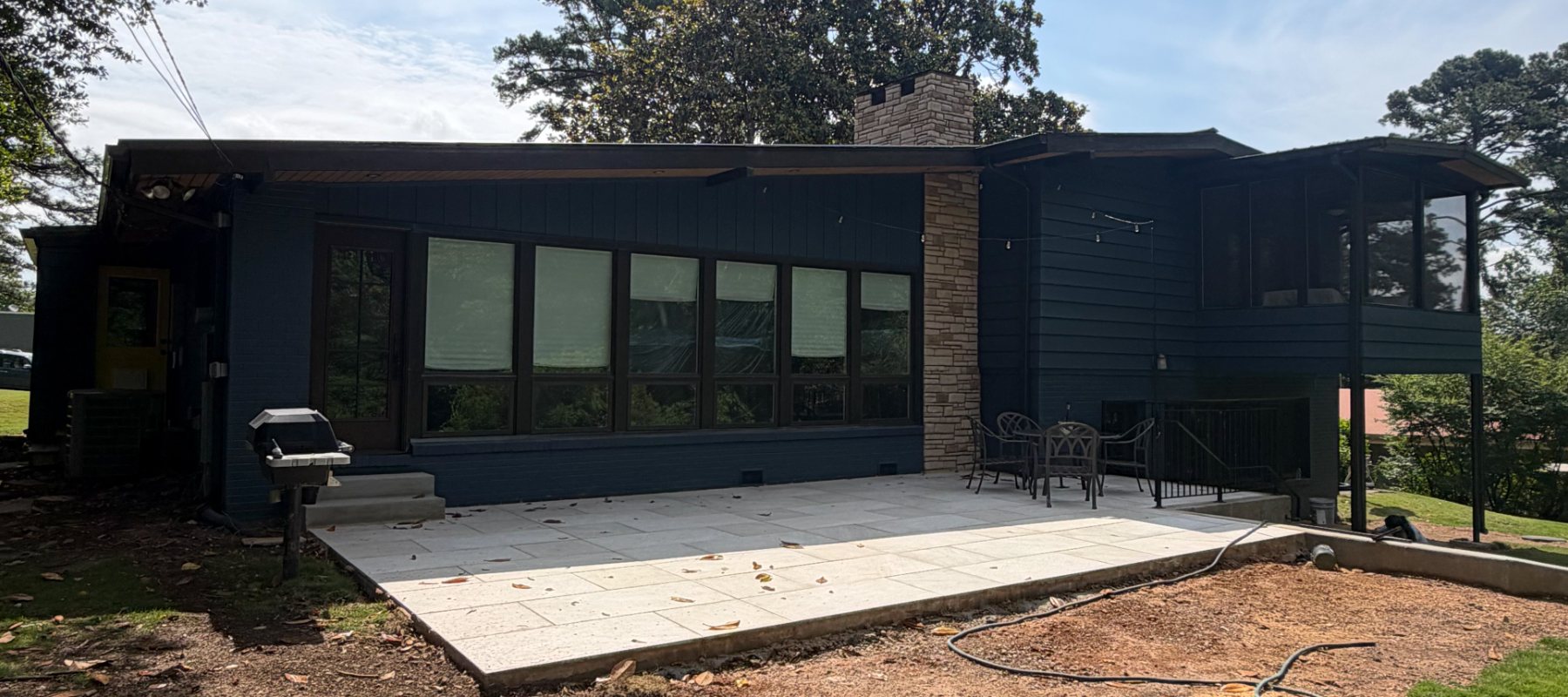 Rear elevation of a home repainted deep navy with a new patio